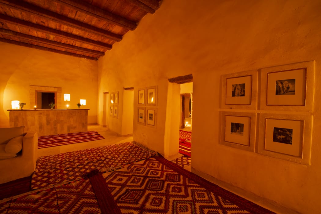 A lamplit Siwan interior with woven rugs and framed photography